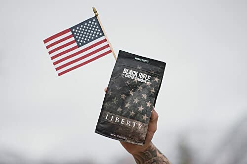 Hand holding Black Rifle Coffee bag with American flag.