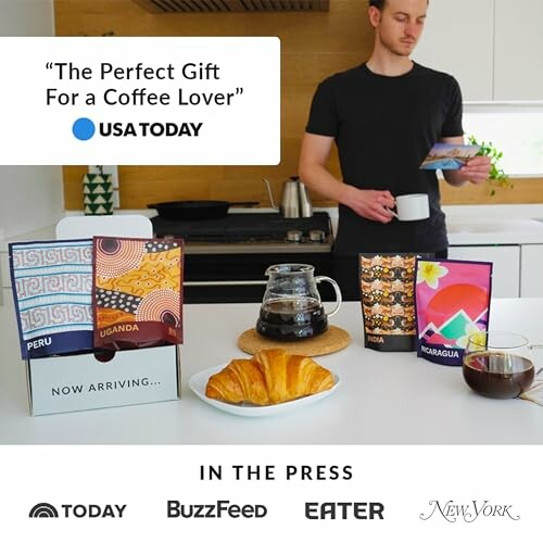 Man in kitchen with coffee gift set and croissant.