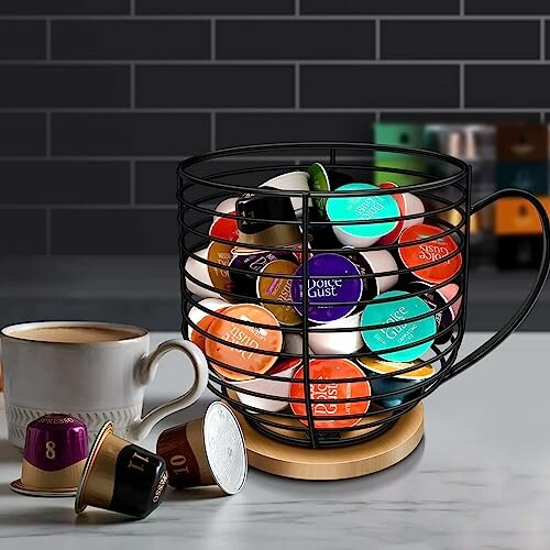 Wire basket filled with colorful coffee pods next to a coffee mug on a countertop