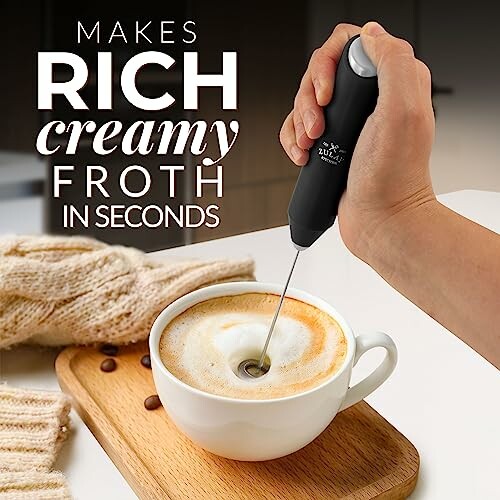 Hand using a milk frother to make frothy coffee.